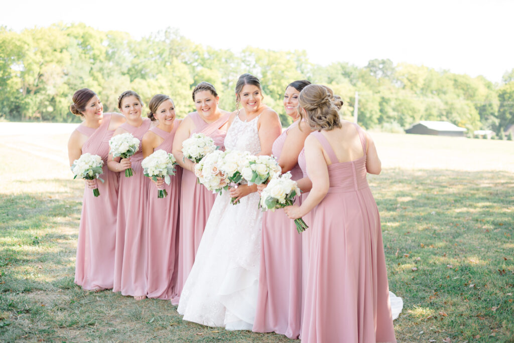 Bride and bridesmaids wearing pink dresses smiling and laughing in Virginia Beach wedding venue