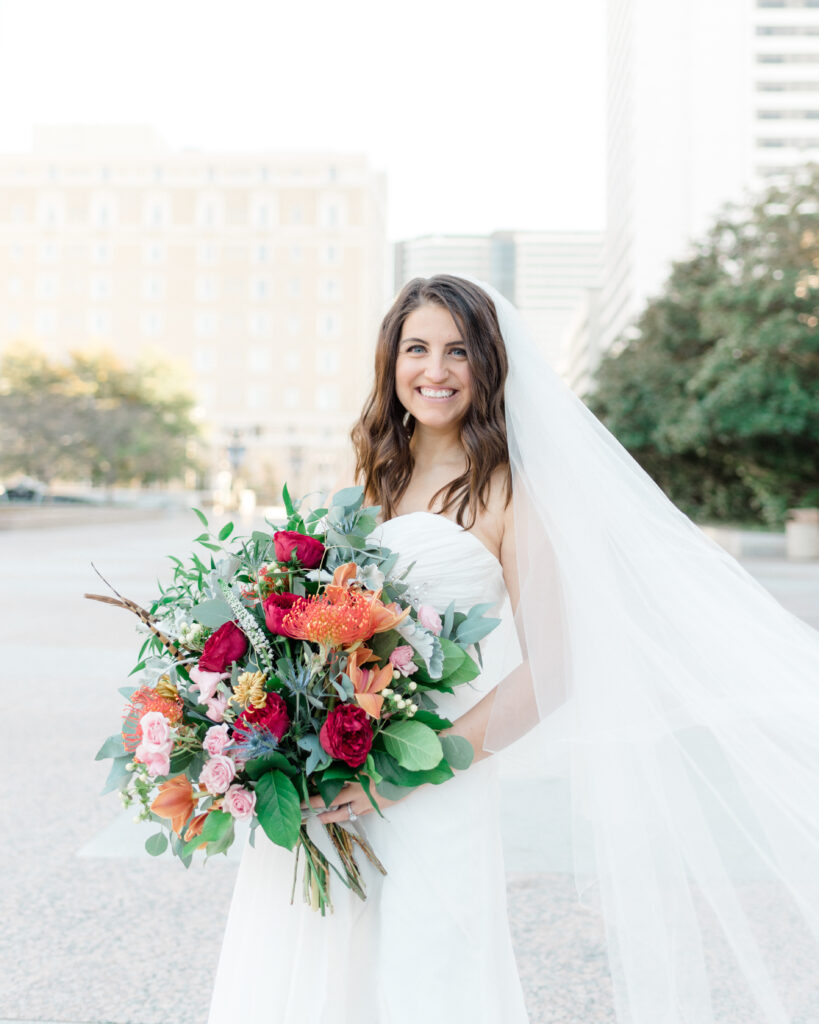 Bride smiling at the camera holding a bouquet of fall flowers in Virginia Beach, Virginia