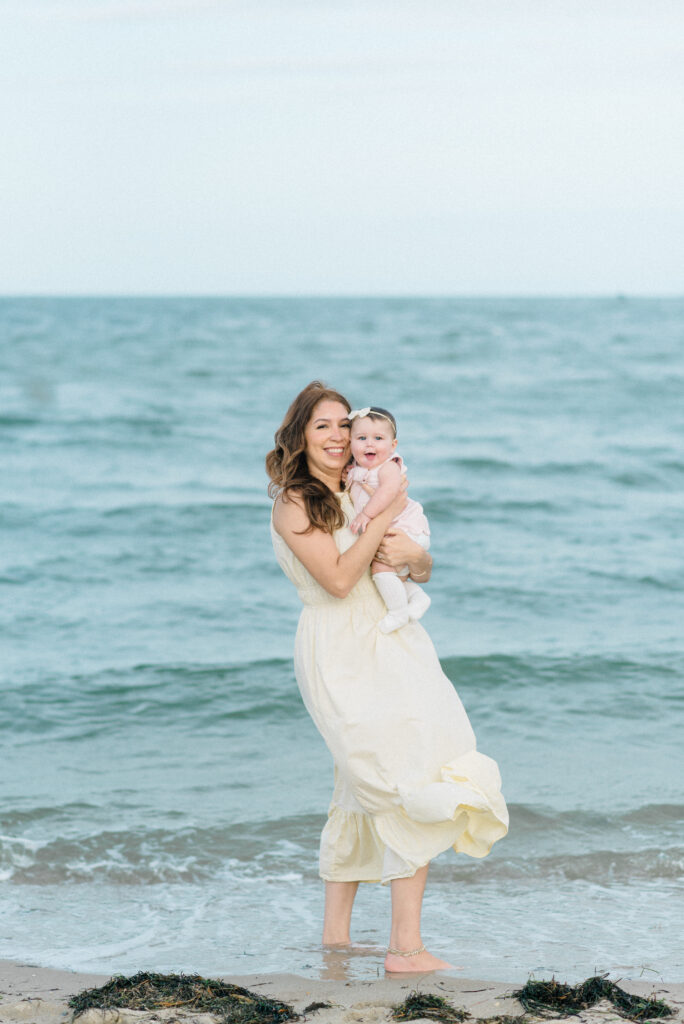 Mom holding her baby during family photos at Yorktown Beach during sunset