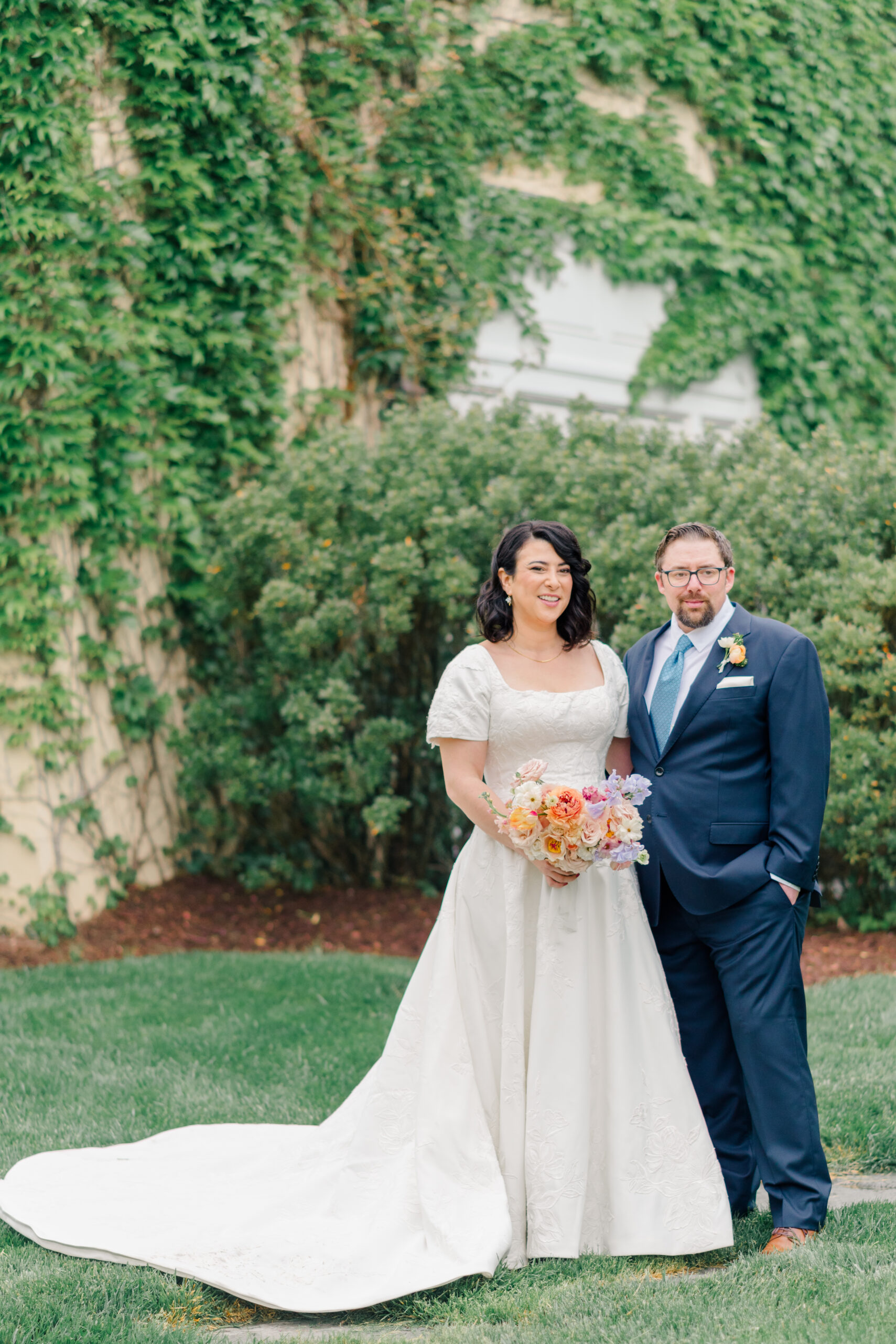 Bride and Groom standing outside an ivy-covered mansion during first look portraits