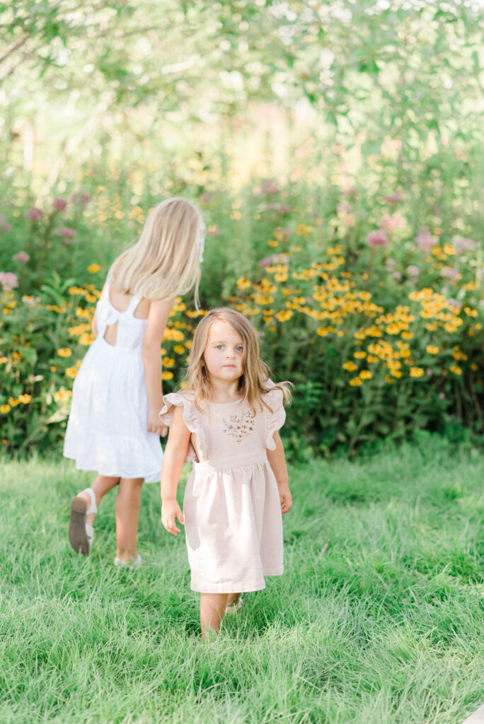 Two sisters picking flowers in the garden during their summer family photos 
